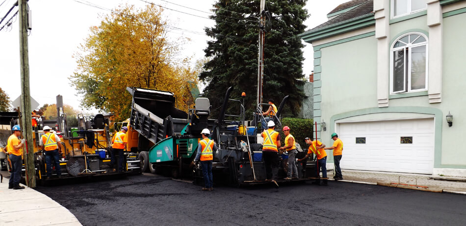 Vue générale sur une équipe de pavage  derrière un camion de chargement d'asphalte